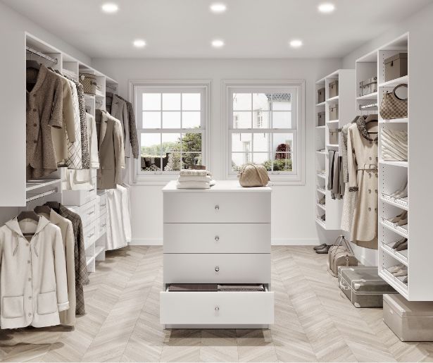 Spacious walk-in closet with white shelves, hanging coats, handbags, storage boxes, and a central dresser with one drawer open. Two windows let in natural light.