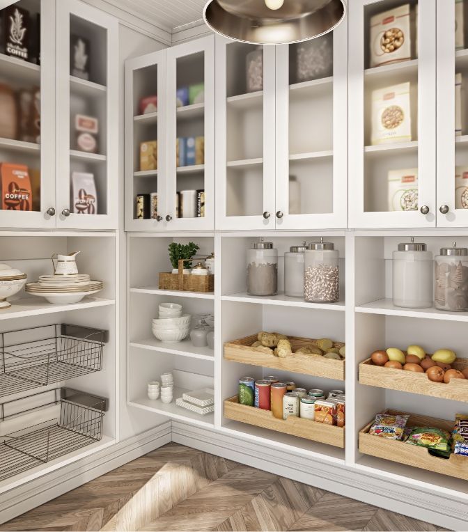 Modern pantry with white cabinets, glass doors, jars of dry goods, baskets of produce, canned foods, cereal boxes, dishes, and wire baskets on wooden shelves. The space has a herringbone wood floor.