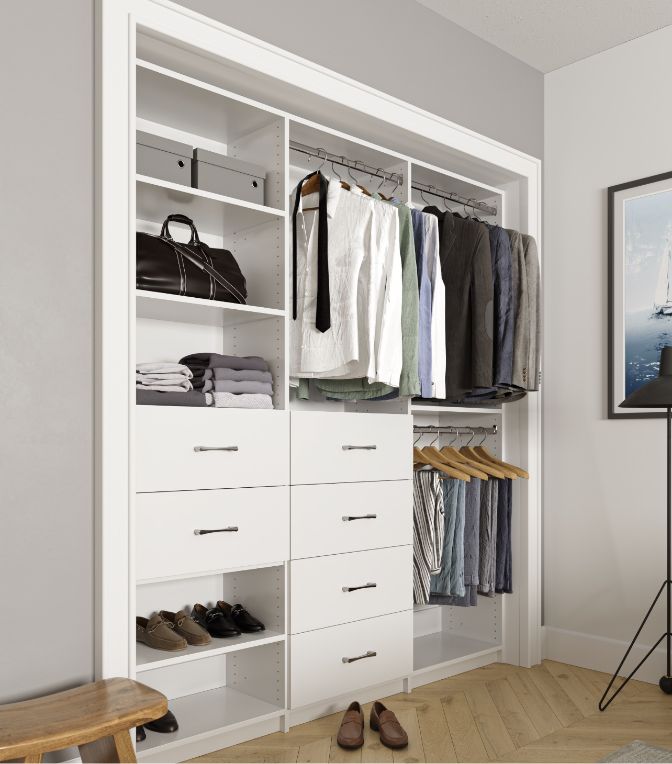 A neatly organized closet with shelves, drawers, hanging clothes, shoes, and bags. The closet is white and built into the wall, with suits, shirts, and pants hanging and several pairs of shoes and folded clothes on shelves.