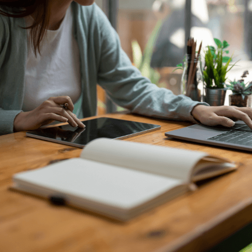 woman planning with notebook and tablet sitting at kitchen table